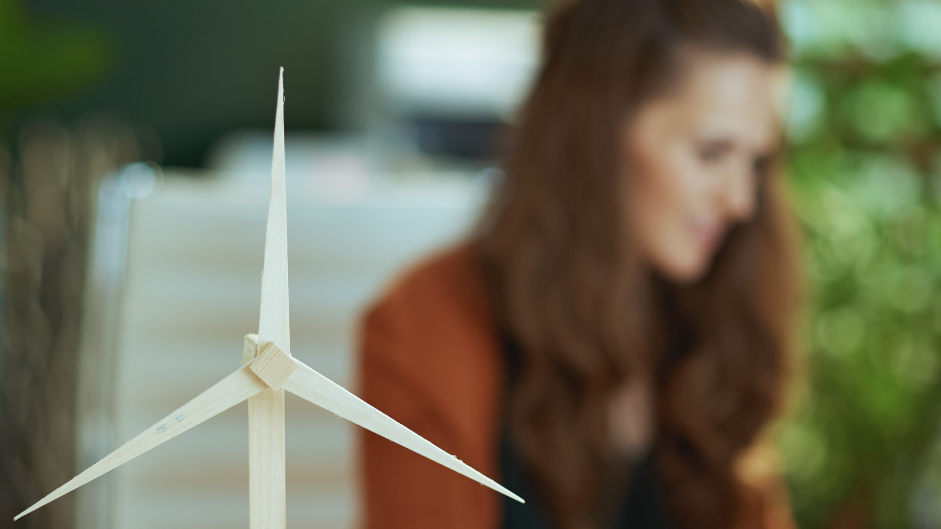 model of wind turbine with woman in background